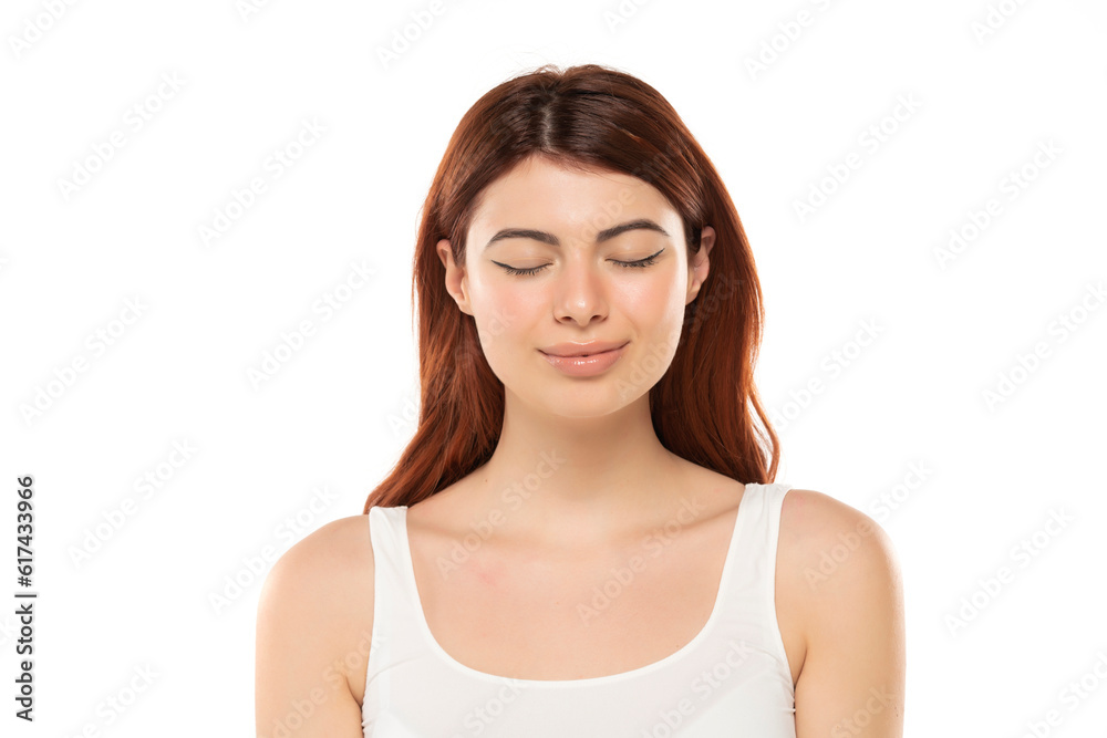 Portrait of smiling beautiful woman with long straight ginger hair and closed eyes on a white background Portrait of smiling beautiful woman with long straight ginger hair and closed eyes on a white background