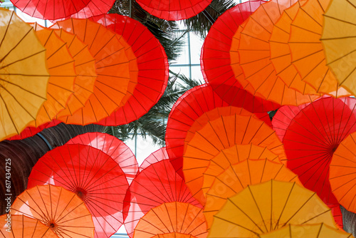 hanging paper umbrella used as decorative spread and looks like wind-chimes, orange and yellow in color. top up view