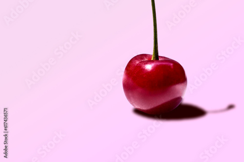 red cherry on a light pink pastel background with copy space