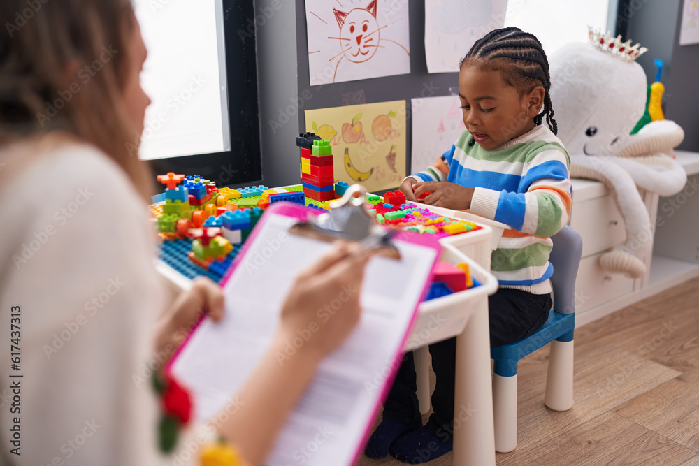 Obraz premium African american boy playing with construction blocks having psychotherapy at kindergarten