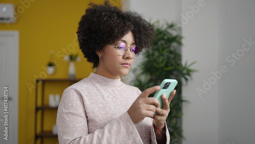 Young african american woman using smartphone stressed at home
