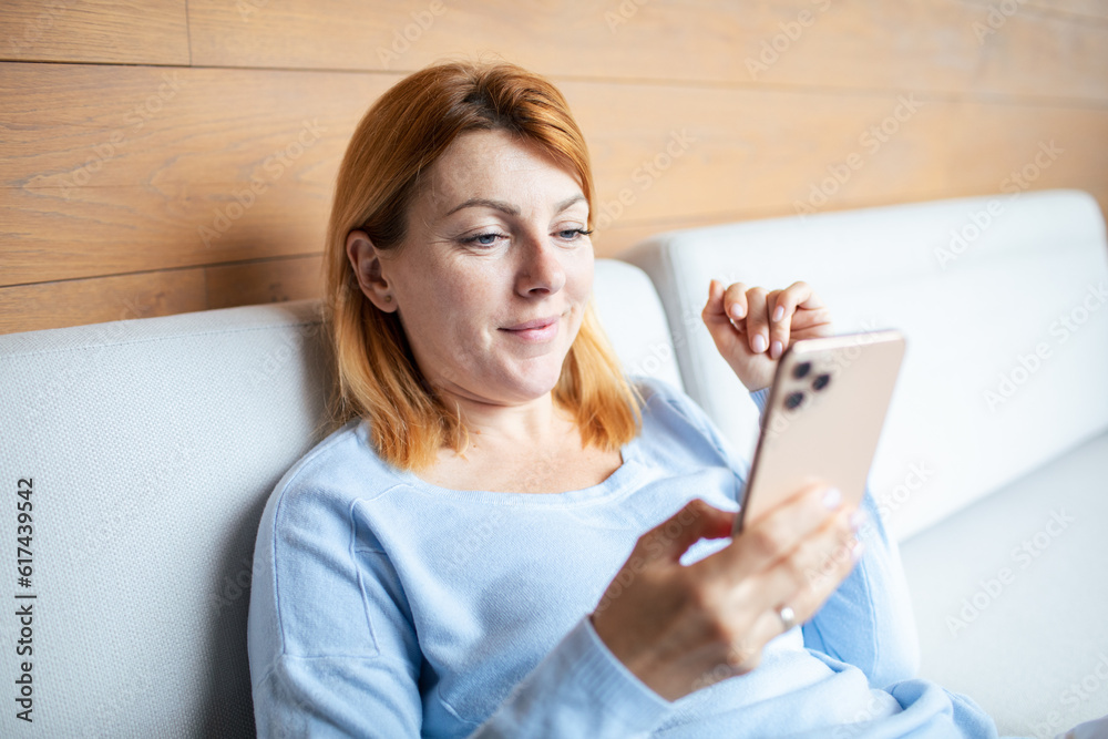 Mid adult woman using a smart phone at home Mid adult woman using a smart phone at home