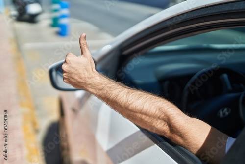 Young caucasian man driving car doing ok gesture with thumb up at street © Krakenimages.com