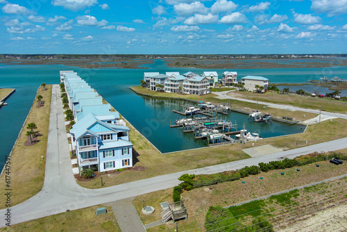Aerial photograph of beach houses lined up along the canals of the intracoastal waterway with a dock and small boats.