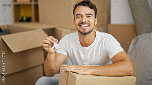 Young hispanic man smiling confident holding new house keys at new home
