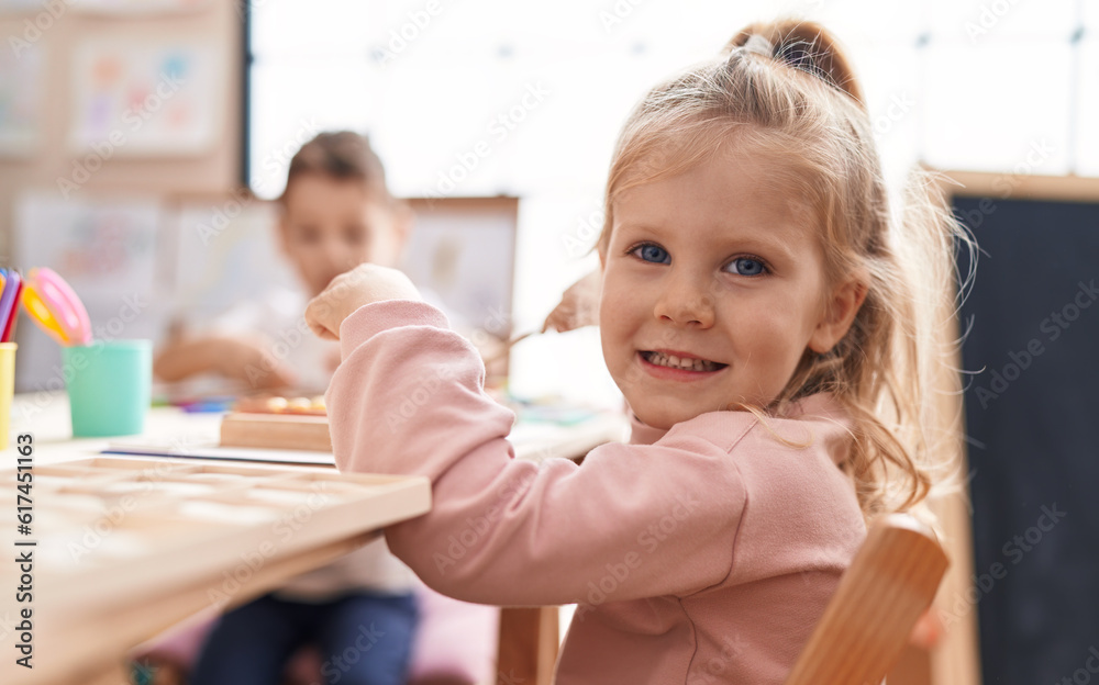 Adorable blonde girl smiling confident sitting on table at kindergarten Adorable blonde girl smiling confident sitting on table at kindergarten