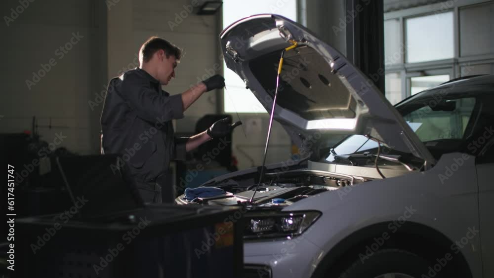 car maintenance, professional male worker checks oil in motor on technical platform car maintenance, professional male worker checks oil in motor on technical platform
