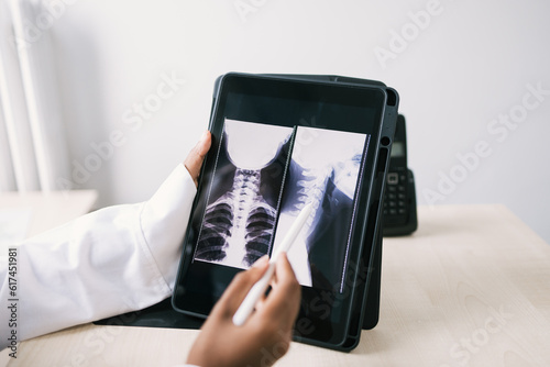 Crop black doctor sitting at table and checking x ray on tablet photo