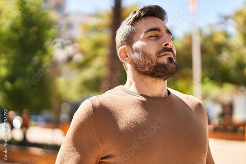 Young hispanic man smiling confident breathing at park photo