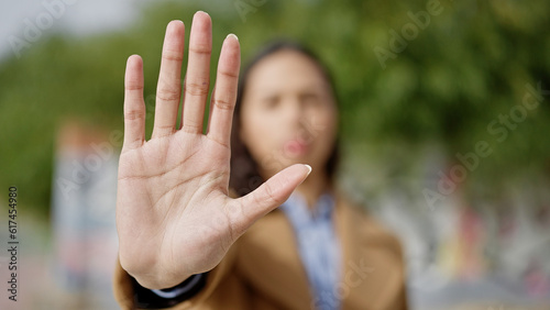 Young beautiful hispanic woman doing stop gesture with hand at park