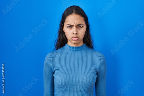 Young brazilian woman standing over blue isolated background skeptic and nervous, frowning upset because of problem. negative person.