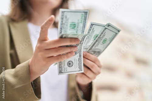 Young woman business worker counting dollars at street