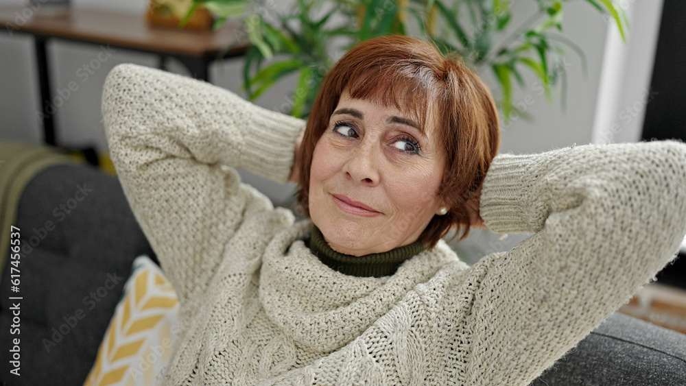 Mature hispanic woman relaxed with hands on head sitting on sofa at home Mature hispanic woman relaxed with hands on head sitting on sofa at home