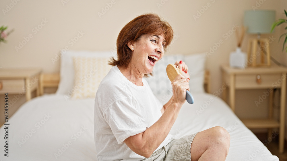 Middle age woman singing song using brush as a microphone at bedroom Middle age woman singing song using brush as a microphone at bedroom