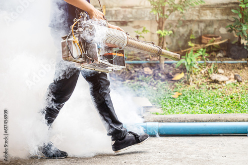 pest control staff spray chemical smoke eliminate mosquito larvae rats cockroach bugs around office building outdoor. photo