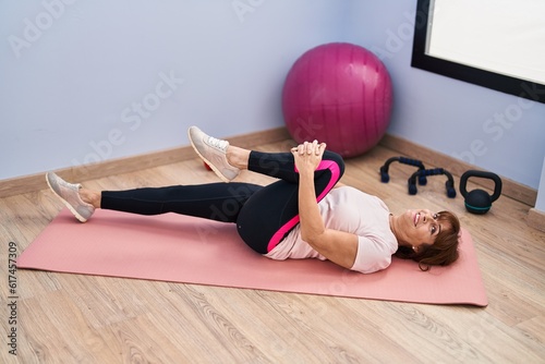 Middle age woman smiling confident stretching leg at sport center