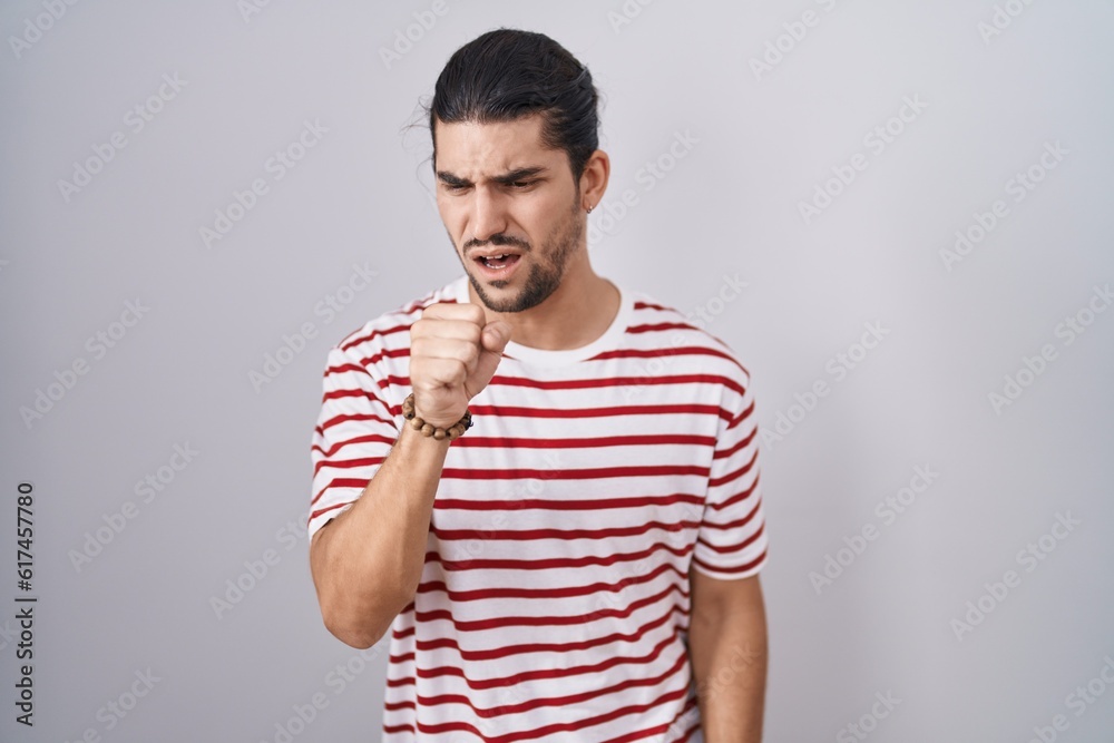 Hispanic man with long hair standing over isolated background feeling unwell and coughing as symptom for cold or bronchitis. health care concept. Hispanic man with long hair standing over isolated background feeling unwell and coughing as symptom for cold or bronchitis. health care concept.