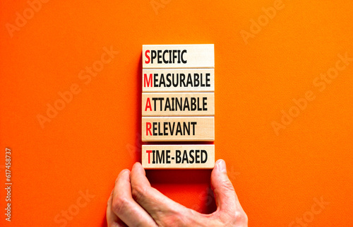 SMART symbol. Concept words SMART specific measurable attainable relevant time-based on block. Beautiful orange background. Business SMART specific measurable attainable relevant time-based concept. photo
