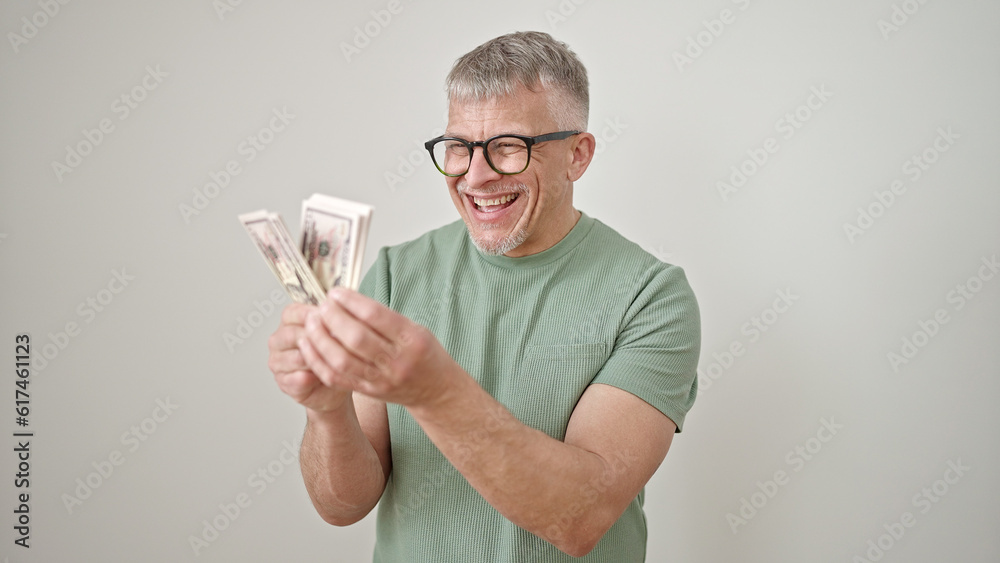 Middle age grey-haired man smiling confident holding dollars over isolated white background Middle age grey-haired man smiling confident holding dollars over isolated white background