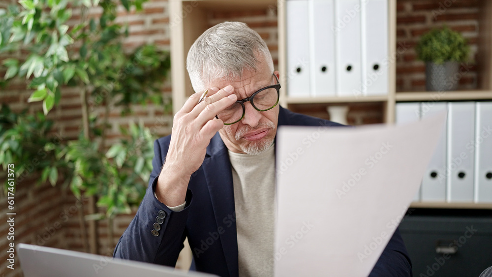 Fototapeta premium Middle age grey-haired man business worker stressed reading document at office