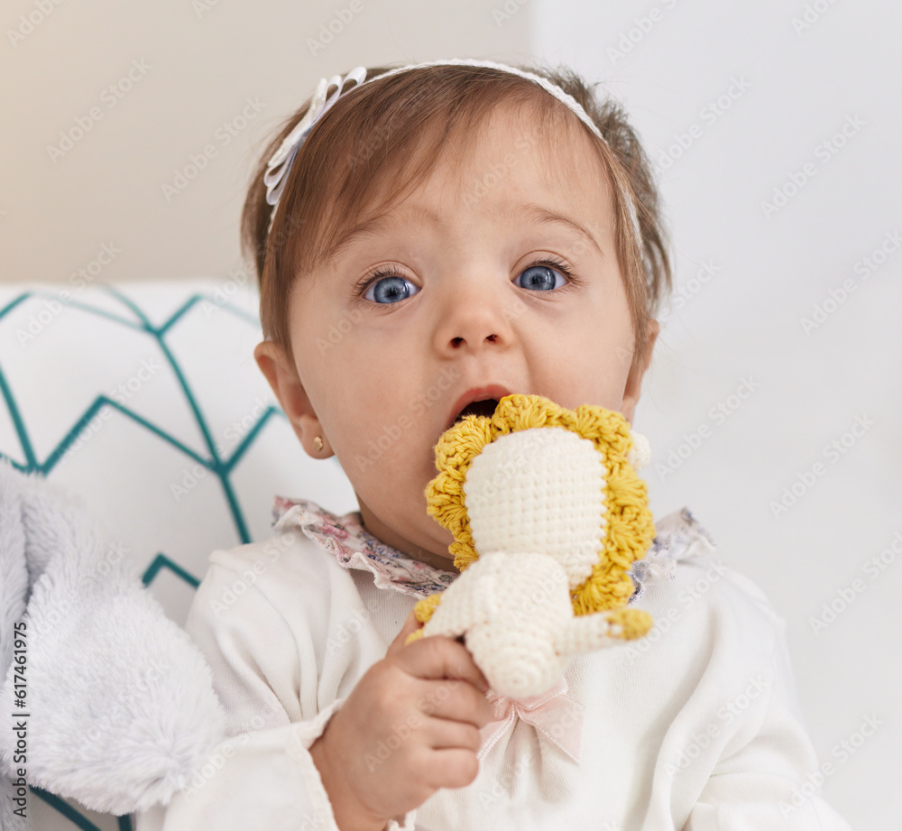 Adorable caucasian baby sitting on bed bitting doll at bedroom Adorable caucasian baby sitting on bed bitting doll at bedroom