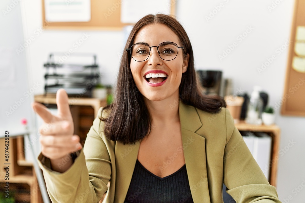 Young beautiful hispanic woman business worker sitting on table speaking at office