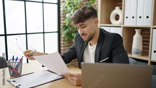 Young arab man business worker using laptop reading document at office