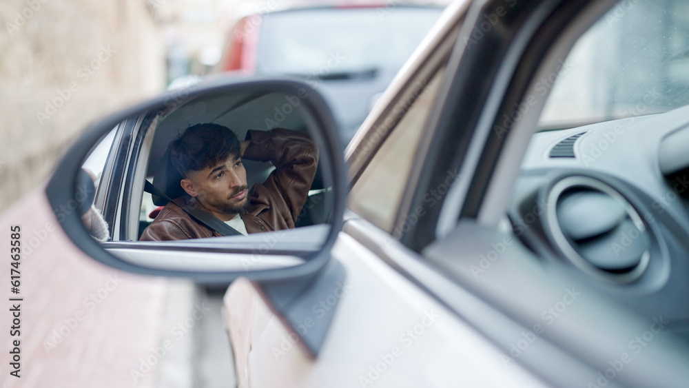 Young arab man sitting on car at street