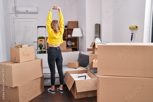 Young blonde woman stretching arms standing on back view at new home © Krakenimages.com