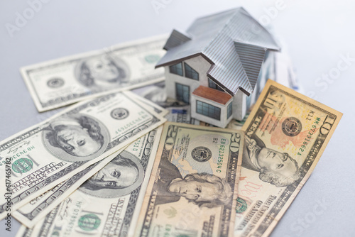 Wooden house model on background of US dollars banknotes. Housing market, purchase or rental of real estate. The concept of buying and selling real estate