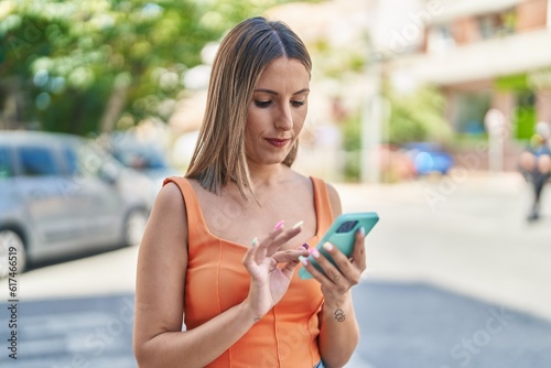 Young beautiful hispanic woman using smartphone with relaxed expression at street