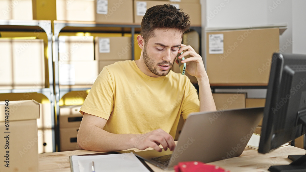 Young hispanic man ecommerce business worker talking on smartphone using laptop at office Young hispanic man ecommerce business worker talking on smartphone using laptop at office