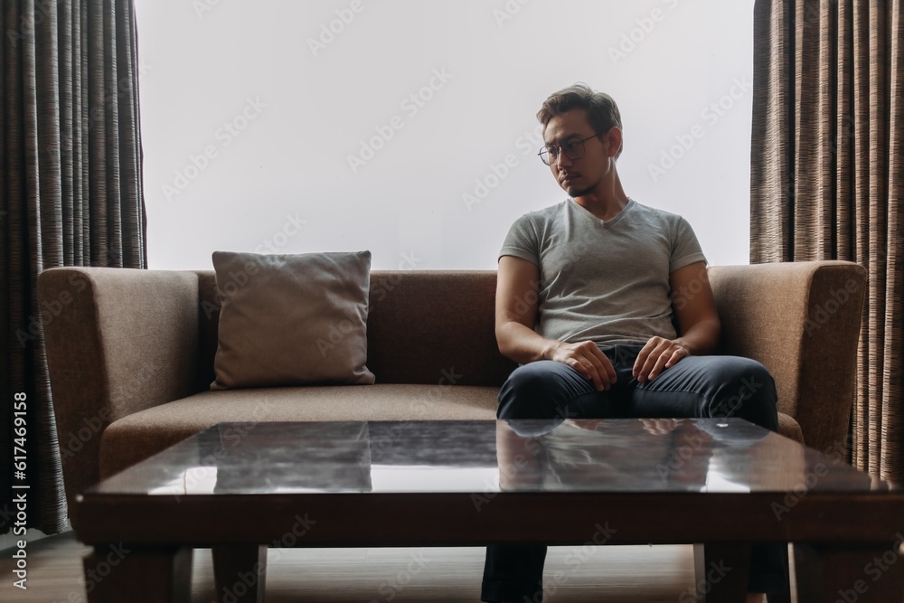 Lonely asian man sits on the sofa thinking of his lover. Lonely asian man sits on the sofa thinking of his lover.