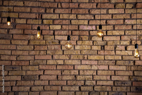Old electric incandescent lamps with tungsten filament. Against the backdrop of a brick wall. Texture of old stone background. Decorative vintage design edison lightbulbs of different shapes. Antique
