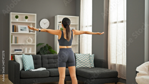 Young beautiful hispanic woman stretching arms training at home