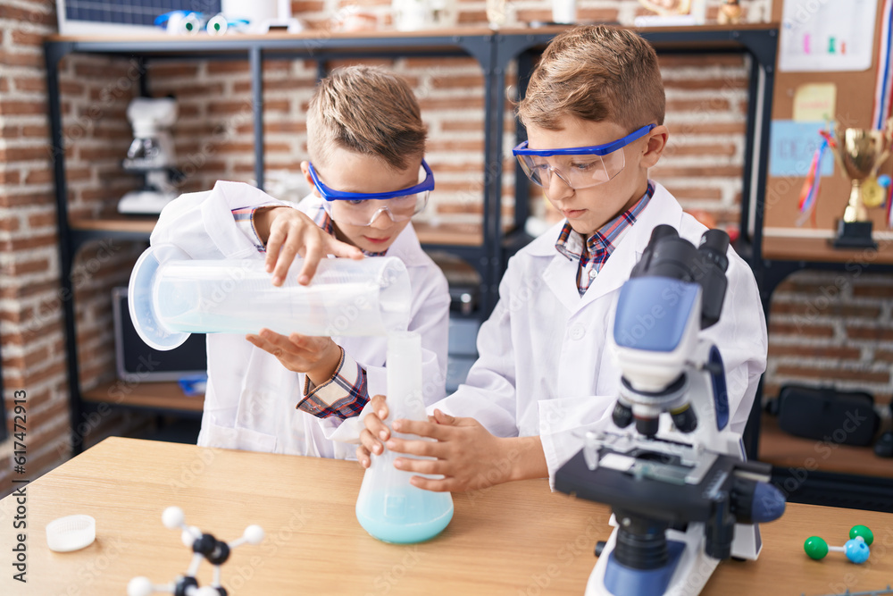 Adorable boys student pouring liquid on test tube at laboratory classroom Adorable boys student pouring liquid on test tube at laboratory classroom
