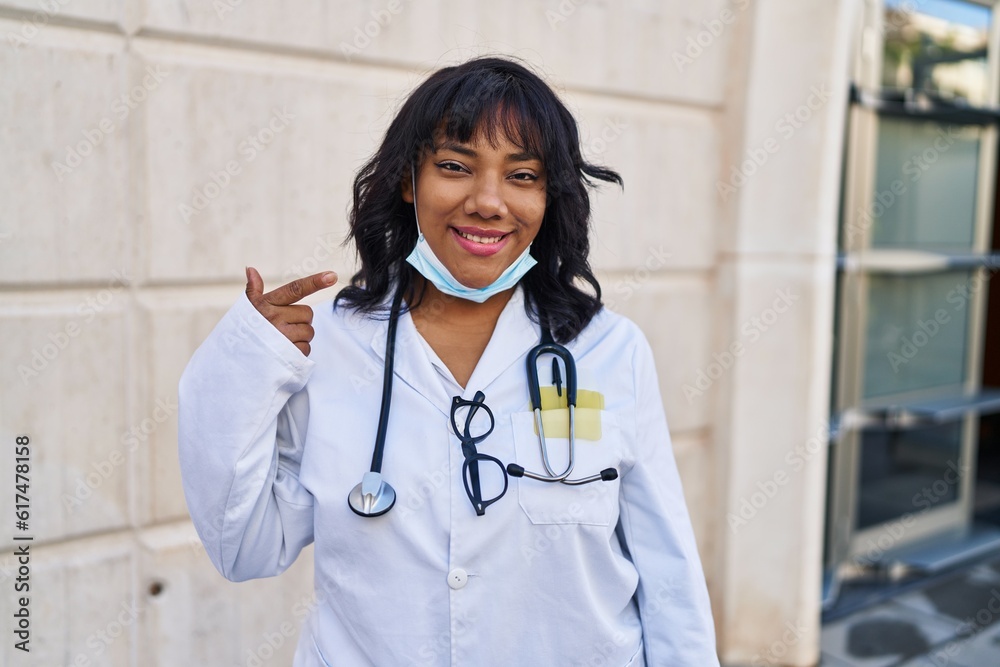 Hispanic doctor woman wearing stethoscope outdoors smiling happy pointing with hand and finger Hispanic doctor woman wearing stethoscope outdoors smiling happy pointing with hand and finger