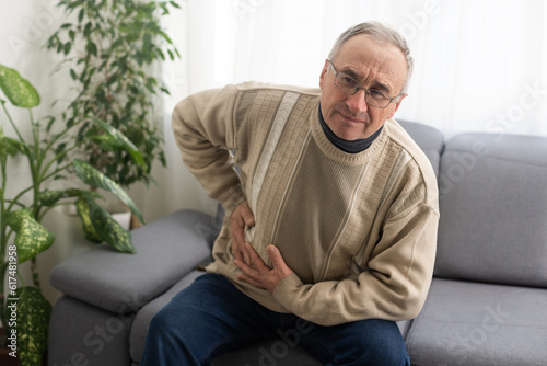 фотографія Elderly men have abdominal pain sitting on the sofa in the house
