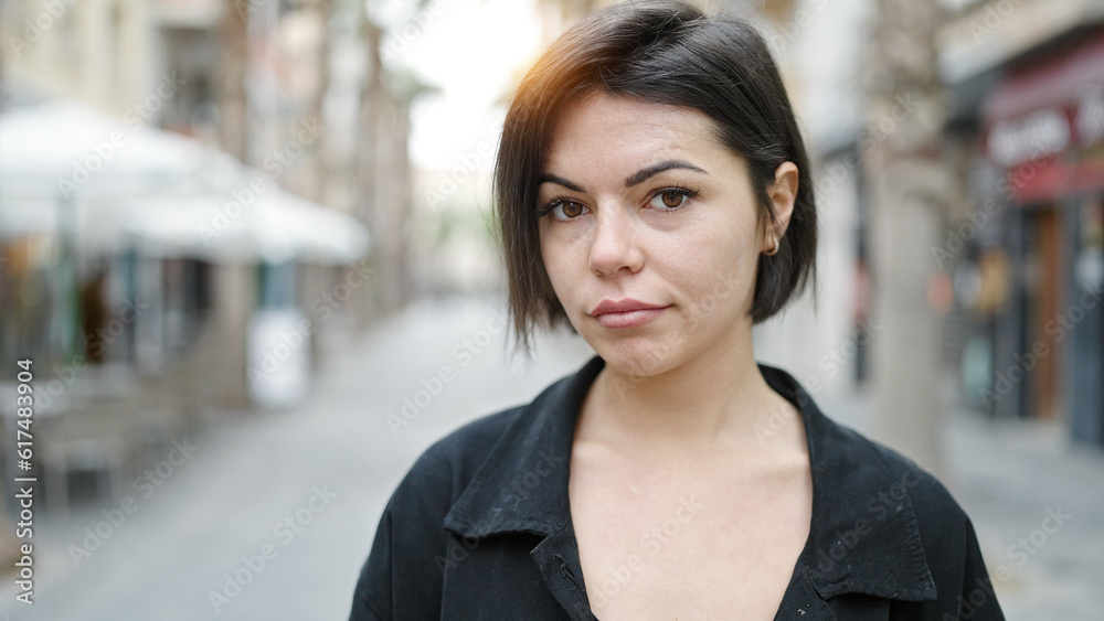 Young caucasian woman standing with serious expression at street