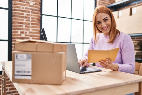 Young caucasian woman ecommerce business worker using laptop holding package at office