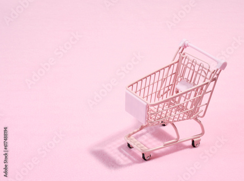 Pink empty shopping cart on a pink background. Copy space for text. Idea of shopping.