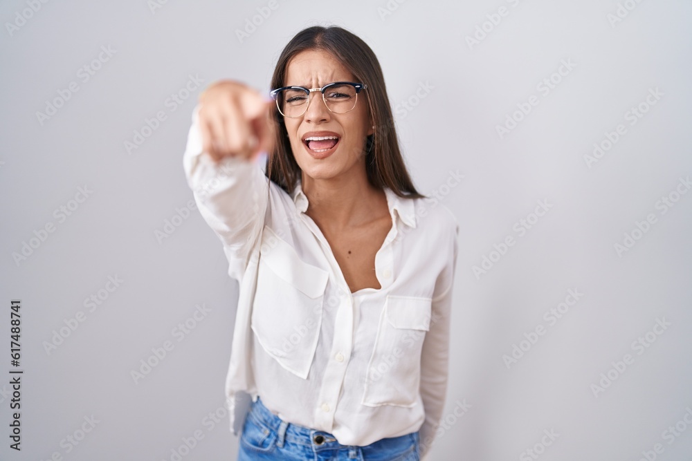 Young brunette woman wearing glasses pointing displeased and frustrated to the camera, angry and furious with you Young brunette woman wearing glasses pointing displeased and frustrated to the camera, angry and furious with you