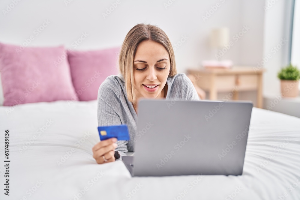 Young woman using laptop and credit card lying on bed at bedroom Young woman using laptop and credit card lying on bed at bedroom