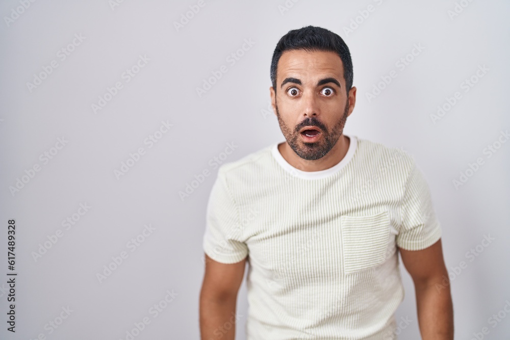 Hispanic man with beard standing over isolated background afraid and shocked with surprise and amazed expression, fear and excited face. Hispanic man with beard standing over isolated background afraid and shocked with surprise and amazed expression, fear and excited face.