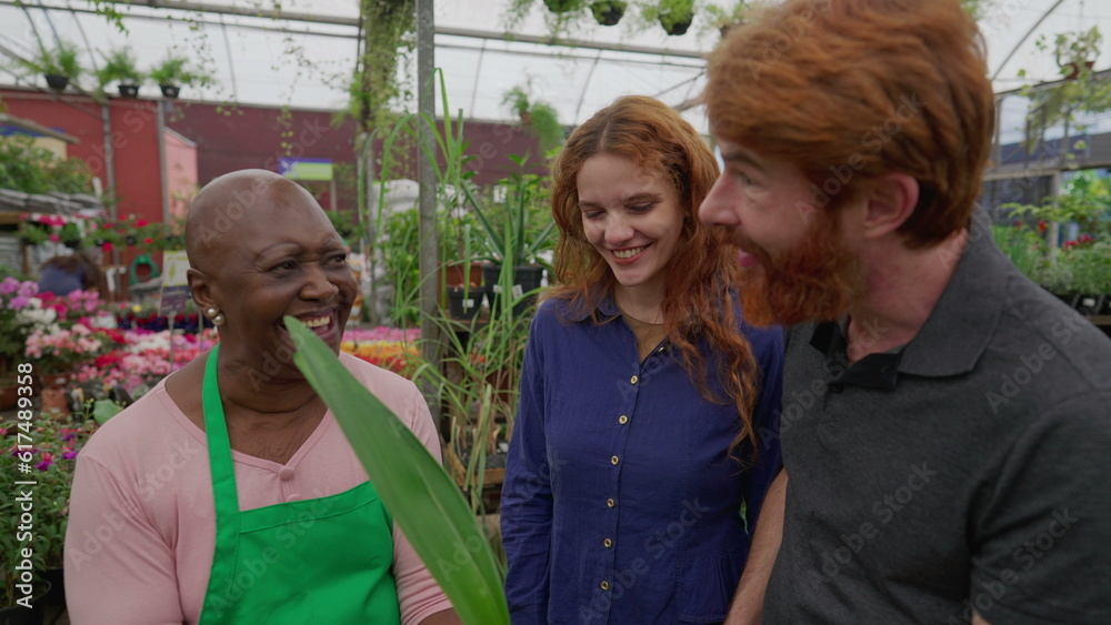 Joyful Couple Shopping for Plants in Flower Shop with a Cheerful Laughing Black Employee