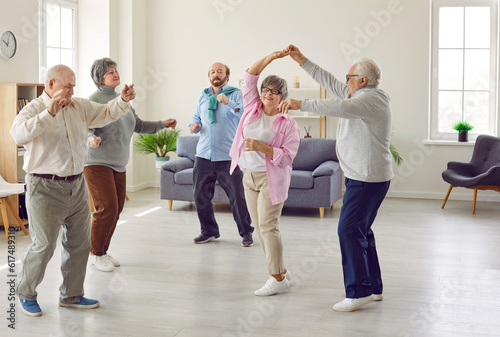 Full length portrait of a group of happy smiling senior people men and women having fun and dancing enjoying activities in retirement home together. Leisure time in nursing home concept.