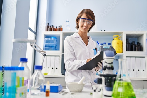 Young beautiful hispanic woman scientist smiling confident writing report working at laboratory