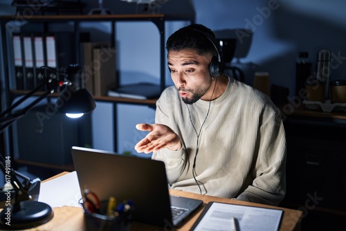 Young handsome man working using computer laptop at night looking at the camera blowing a kiss with hand on air being lovely and sexy. love expression.