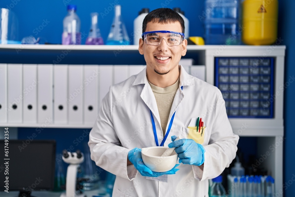 Young arab man working at scientist laboratory smiling and laughing hard out loud because funny crazy joke.