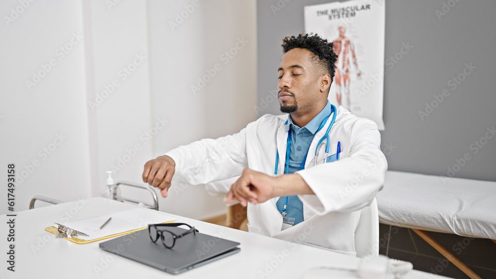 African american man doctor sitting on table with serious expression at street